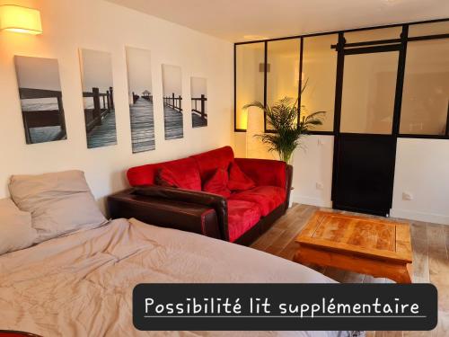 a bedroom with a bed and a red couch at Appartement calme et pratique. in Tours