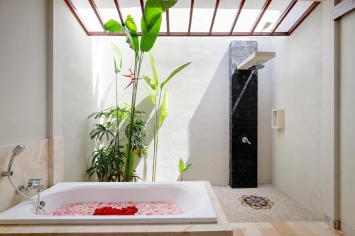 a bath tub in a bathroom with a plant at Lumbini Luxury Villas and Spa in Jimbaran