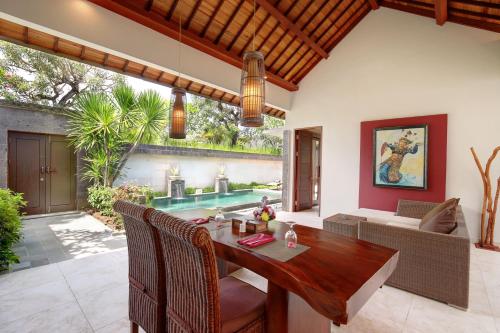 a dining room with a table and a pool at Lumbini Luxury Villas and Spa in Jimbaran