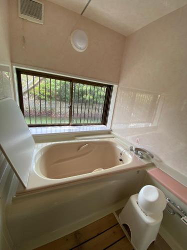 a bath tub in a bathroom with a window at BAYMARINAログハウス in Sakaide