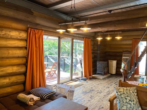 a living room with wooden walls and a large window at BAYMARINAログハウス in Sakaide