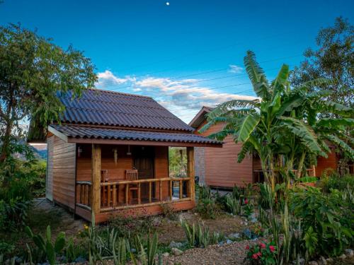 een houten huis met een terras in een tuin bij Nana Bungalows in Ban Tan