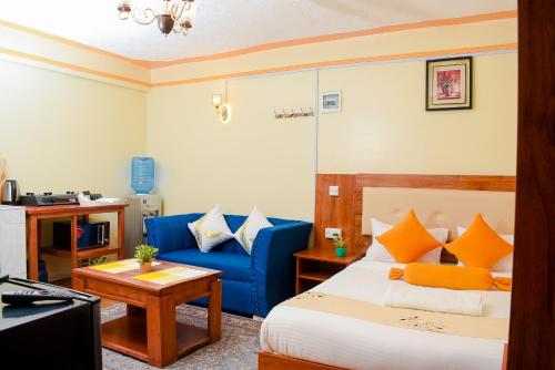 a hotel room with a bed and a blue couch at Shalom Apartments in Naivasha