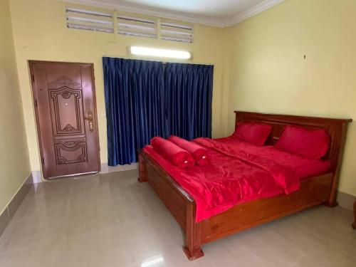 a bedroom with a bed with red sheets and a door at 88 Apartment Sen Sok in Phnom Penh