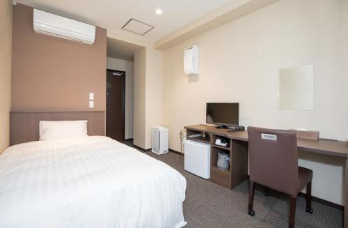 a hotel room with a bed and a desk with a computer at Kur and Hotel Isawa in Fuefuki