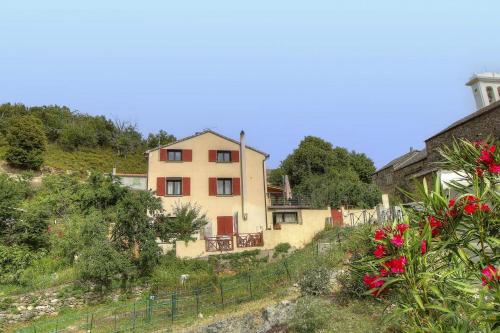 a house on the side of a hill with flowers at Chambre d'hôtes couvent d'Alando in Alando