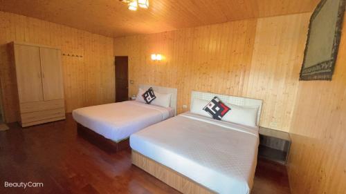 two beds in a room with wooden walls at 寧靜的家A區14人Villa獨立設施包棟戲水池烤肉區麻將廚房私人停車場 in Hengchun South Gate