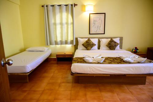 a bedroom with two beds with white flowers on them at Lifestyle villa in Candolim