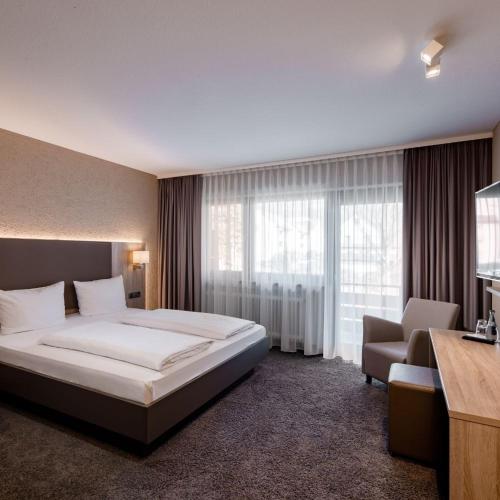 a hotel room with a bed and a chair and window at Gästehaus Becher in Donzdorf