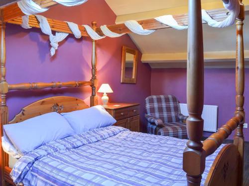 een slaapkamer met een hemelbed en een paarse muur bij Birkerthwaite Barn-w41478 in Eskdale