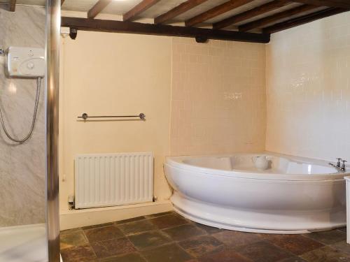 een groot wit bad in een badkamer met een douche bij Birkerthwaite Barn-w41478 in Eskdale