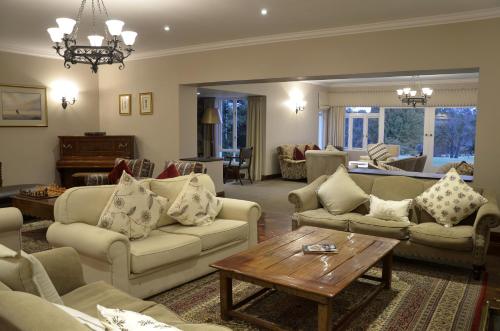 a living room with couches and a table at Lythwood Lodge in Lidgetton