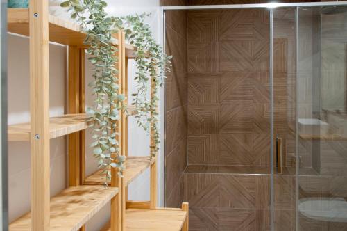 a shower room with wooden shelves and a glass door at Felipe Antón Suites in Mutxamel