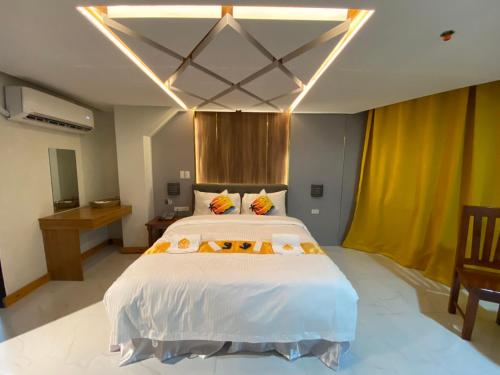 a bedroom with a large white bed with yellow curtains at NGN Gran Hotel in Tuguegarao City