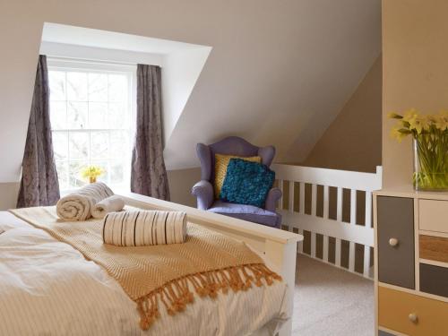 a bedroom with a bed and a blue chair at Stable Cottage in Margate