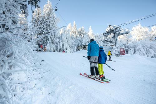 a couple of people on skis on a ski lift at Hotel Monínec in Moninec