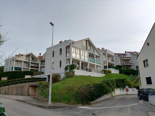 een groot wit huis bovenop een grasheuvel bij Precioso apartamento con piscina en la playa in Mogro