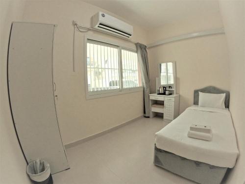 een slaapkamer met een bed, een spiegel en een raam bij Hor Al Anz Star Residence - Home Stay in Dubai
