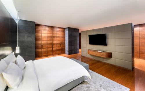a bedroom with a white bed and a flat screen tv at La Cigale Hotel Managed by Accor in Doha