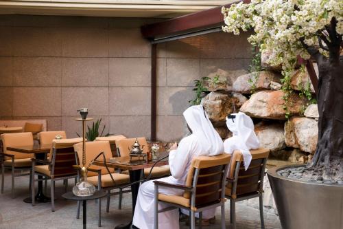 two people sitting at a table in a restaurant at La Cigale Hotel Managed by Accor in Doha