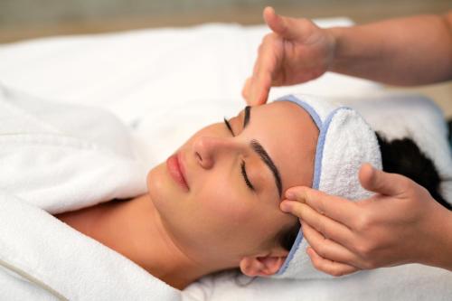 a woman getting her face massage in a towel at La Cigale Hotel Managed by Accor in Doha