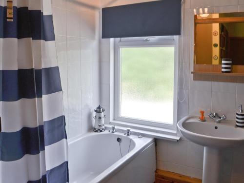 baño con bañera, lavabo y ventana en Isabella Cottage en Heddon on the Wall