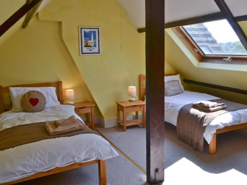 a attic bedroom with two beds and a window at Isabella Cottage in Heddon on the Wall