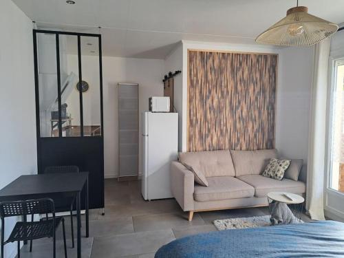 ein Wohnzimmer mit einem Sofa, einem Tisch und einem Kühlschrank in der Unterkunft Studio dans maison avec jardin et balcon, au calme in Sérézin-du-Rhône