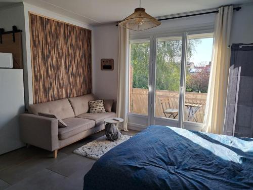 een slaapkamer met een bed, een bank en een raam bij Studio dans maison avec jardin et balcon, au calme in Sérézin-du-Rhône