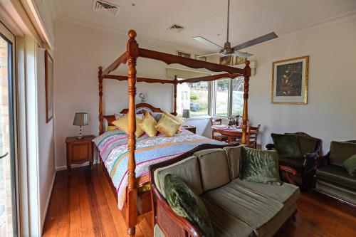 1 dormitorio con cama con dosel y sofá en Galahad's Animal Sanctuary B&B en Gisborne