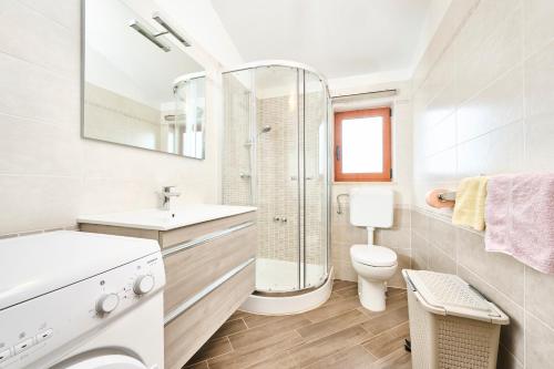 a white bathroom with a sink and a toilet at Elia Apartments in Savudrija
