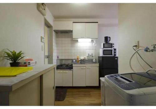 een keuken met witte kasten en een zwarte koelkast bij Palace Mercy105 - Vacation STAY 11922 in Kugayama