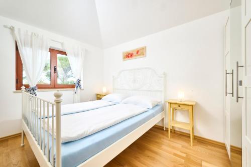 a white bedroom with a bed and a window at Elia Apartments in Savudrija