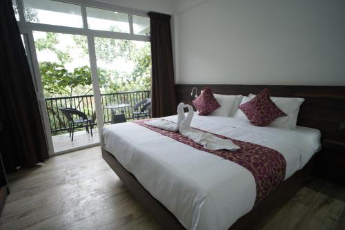 a bedroom with a large bed and a balcony at Villa 75 in Vagamon