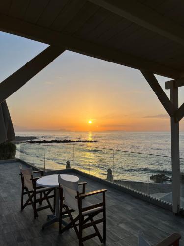 a table and chairs on a balcony with a sunset at Nautica Hotel Apartments in Stavromenos