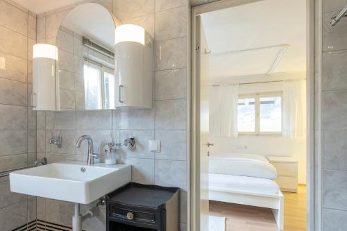 La salle de bains est pourvue d'un lavabo, d'un lit et d'un miroir. dans l'établissement Ferienwohnung Alprima, à Vandans