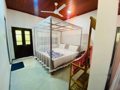 a bedroom with a canopy bed with a ceiling fan at drongo place in Dickwella