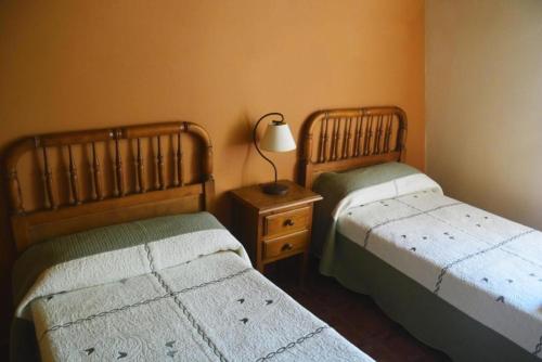 um quarto com 2 camas e um candeeiro numa mesa de cabeceira em Casa Rural Concejo 1 em La Adrada