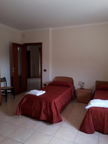 a bedroom with two beds with red sheets and a mirror at B&B Porta del Gargano in San Marco in Lamis