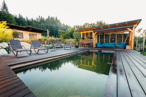 a house with a pool and a deck with chairs at Villa Blumegg in Hermagor
