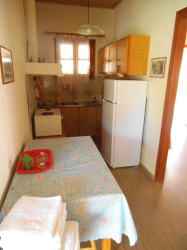 a kitchen with a table and a white refrigerator at Villa Xenos in Kalamaki