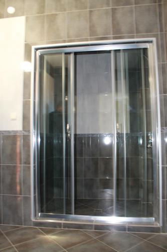 a glass shower door in a tiled wall at Leshtenski Perli in Leshten