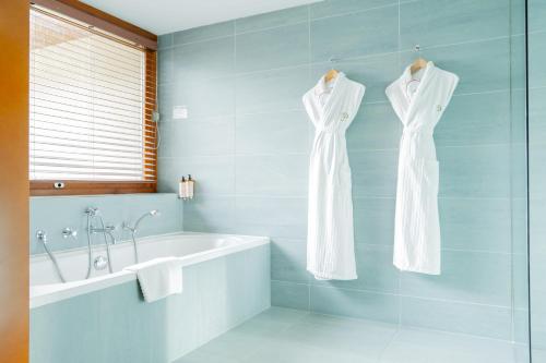 a bathroom with two white dresses hanging on a wall at Le Manoir du Lys, The Originals Relais in Bagnoles de l'Orne