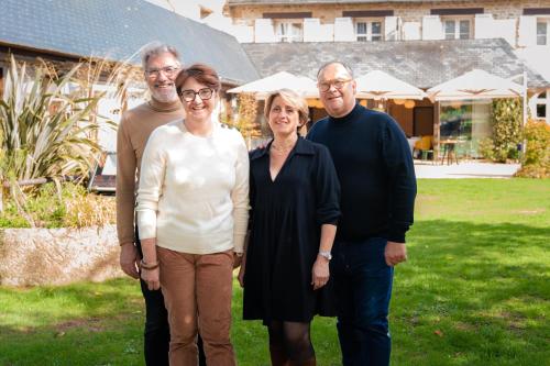 a family posing for a picture in front of a house at Le Manoir du Lys, The Originals Relais in Bagnoles de l'Orne