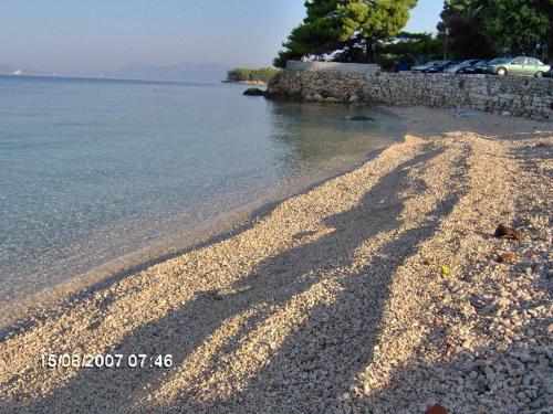 a shadow of a person on the shore of a beach at Adria Apartments in Podgora