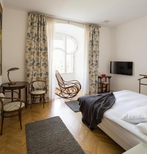 a bedroom with a bed and a tv and chairs at Villa Csonka by Privo in Târgu-Mureş