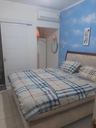 1 dormitorio con 1 cama con pared azul en Villa kota bunga puncak, en Cianjur