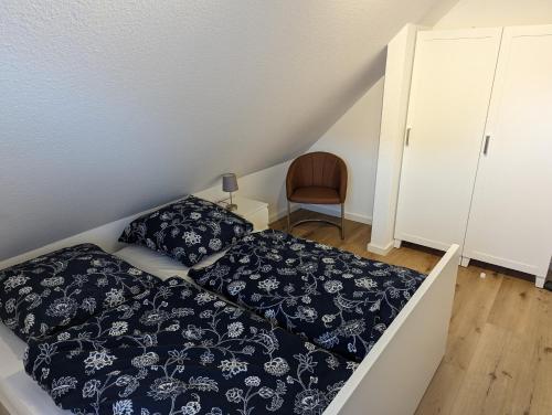 - une chambre mansardée avec un lit et une chaise dans l'établissement Dünengras, à Horumersiel
