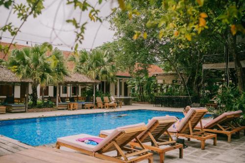 a swimming pool with lounge chairs and a resort at The Banana Tree Hostel in Ninh Binh