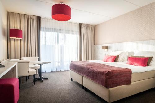 Cette chambre comprend un grand lit et un bureau. dans l'établissement Hotel Boschrand, à De Koog